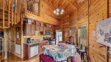 L’intérieur d’un chalet en bois comprend une cuisine, un coin repas et un balcon.