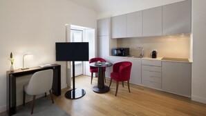 Una cocina compacta con comedor, un televisor de pantalla plana y una cafetera.