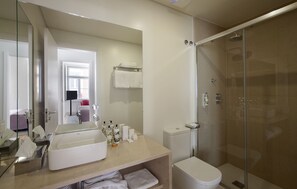 A modern bathroom with a glass-enclosed shower, a sink with a mirror, and a toilet. - Grape Harbor Prata Apartments (Lisbon)