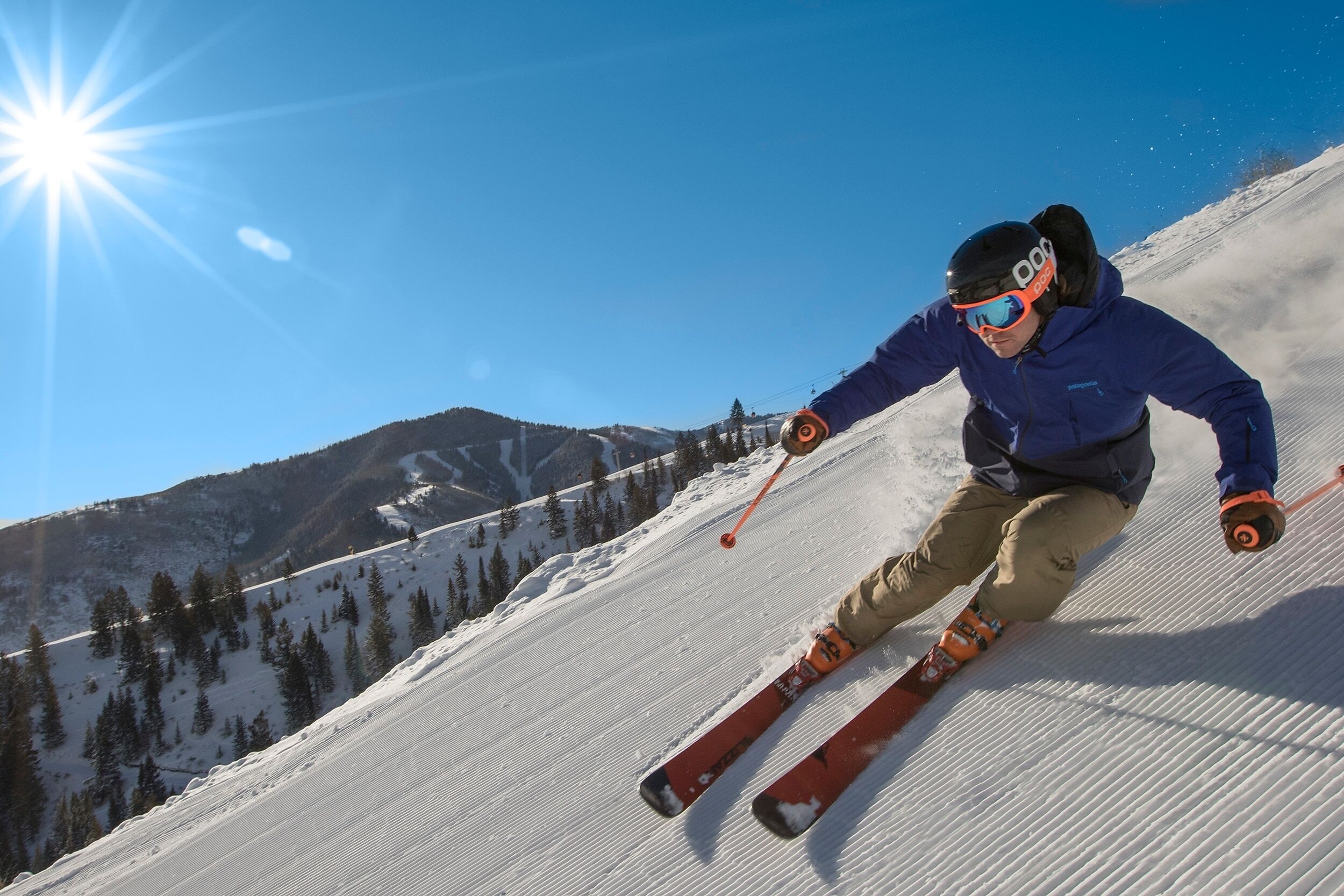 A skier on a snowy slope with a clear sky.