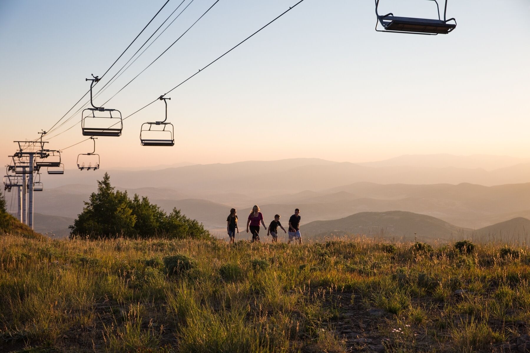 A mountain landscape with a ski lift and a group of people walking.