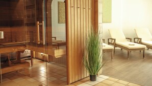 Zona de spa con mobiliario de madera, una mampara de vidrio y una planta en maceta.