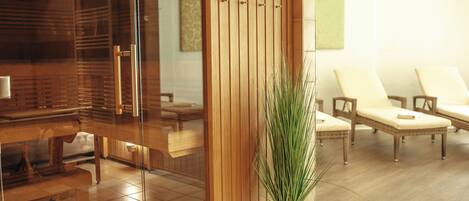 Zona de spa con mobiliario de madera, una mampara de vidrio y una planta en maceta.