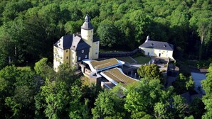 Vista aérea de un castillo con una torre, rodeado de un bosque denso.
