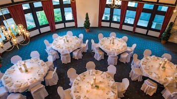 A circular dining area with round tables, white tablecloths, and white chairs.