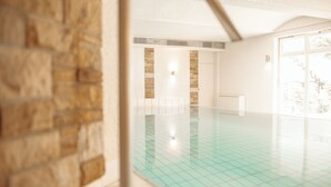 Una piscina con piso de baldosas y pared de piedra.
