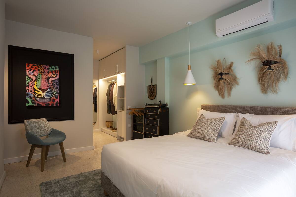 Quarto com cama, uma cadeira, guarda-roupa e ar condicionado fixado na parede.