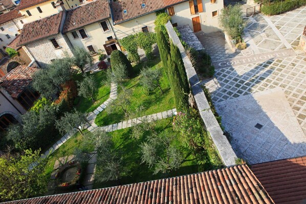 A courtyard with a cobblestone path, surrounded by buildings with terracotta roofs and stone walls.