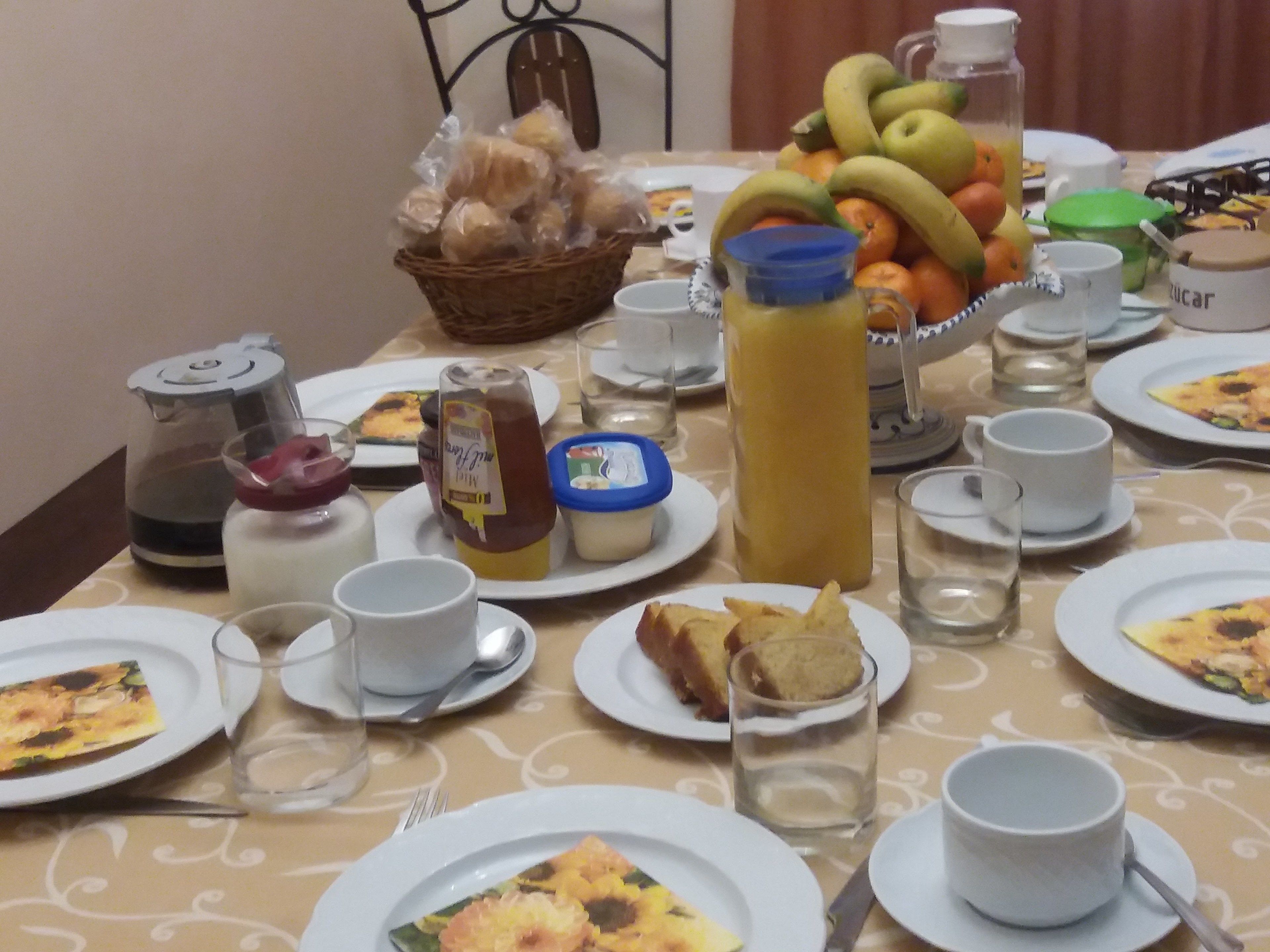 A breakfast table set with plates of food, a pitcher of juice, and various condiments.