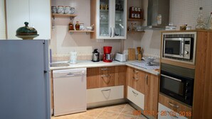 A kitchen with a dishwasher, microwave, oven, and various cabinets and shelves. - Posada la Reja (Malpica de Tajo)