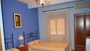 A bedroom with two beds, a nightstand, a lamp, a wardrobe, and a window with sheer curtains. - Posada la Reja (Malpica de Tajo)