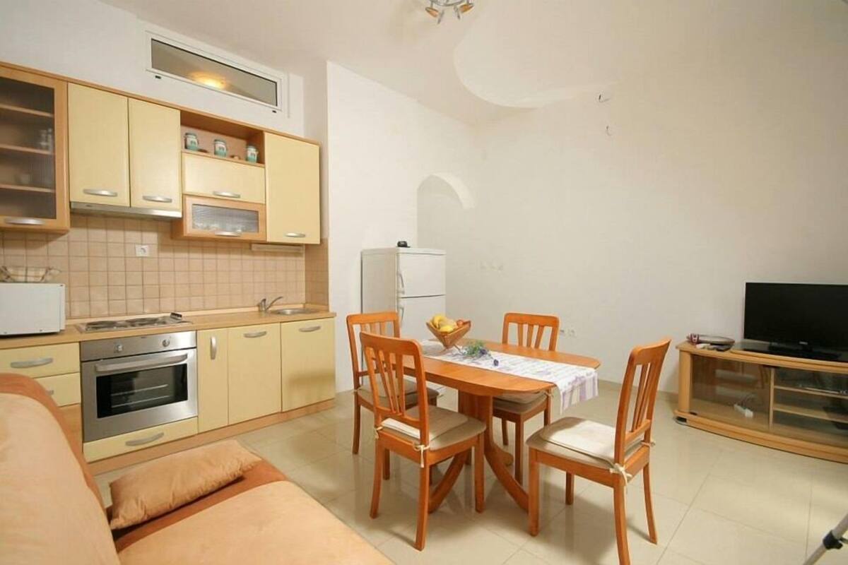 Una cocina compacta con comedor, refrigerador y televisor.