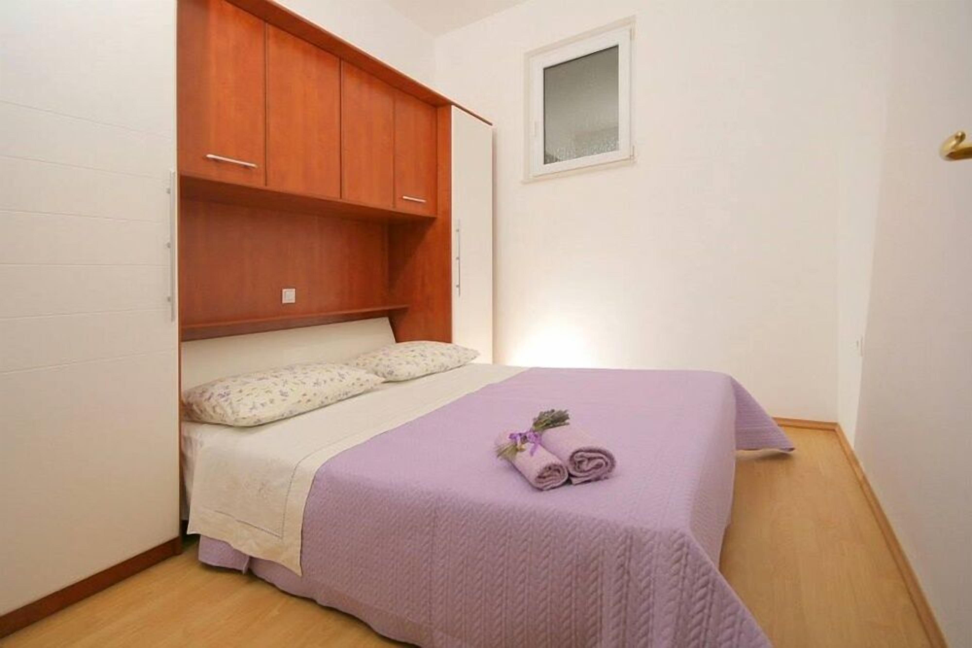Een slaapkamer met een bed, een houten garderobe en een klein raam.