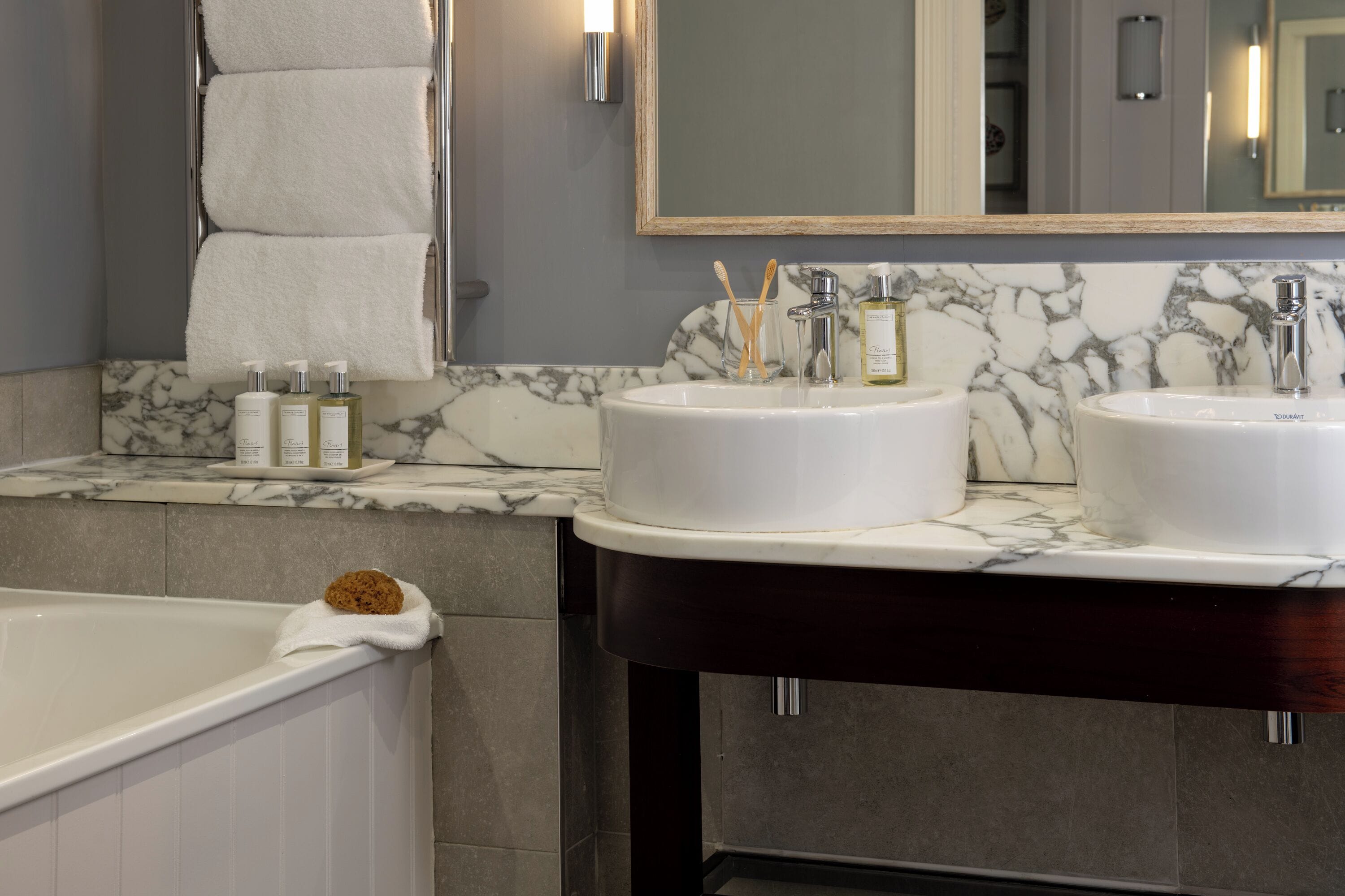 A bathroom with two sinks, a bathtub, and a marble countertop.