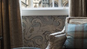 A room with a view of a historic building through a large window, a sofa with patterned upholstery, and a glass table. - Beverley Arms Hotel (Beverley)