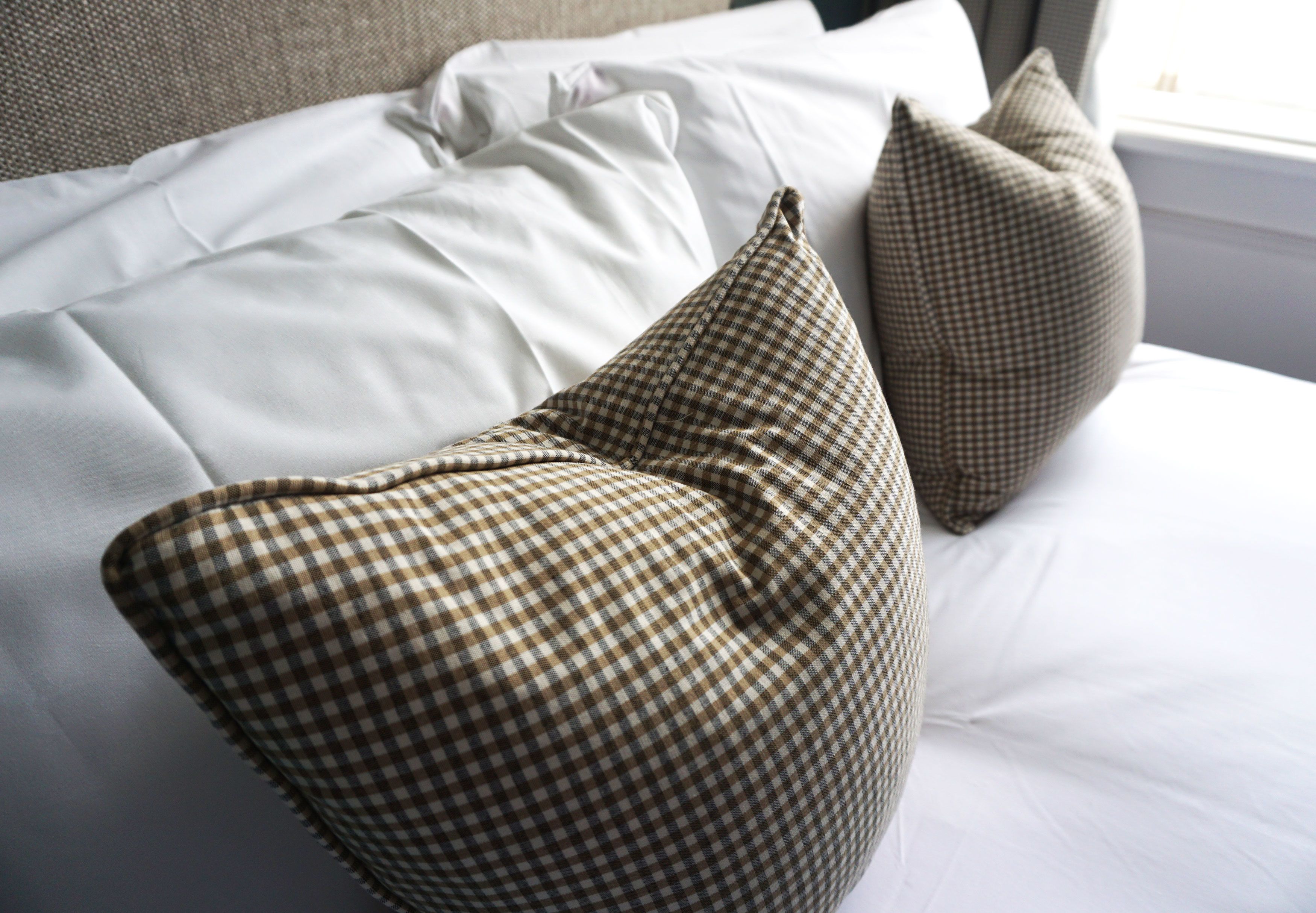 Ein Bett mit weißer Bettwäsche und zwei karierten Kissen.