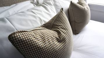 Una cama con sábanas blancas y dos almohadas a cuadros.
