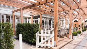 A covered outdoor seating area with wooden pergolas, tables, and chairs. - Beverley Arms Hotel (Beverley)
