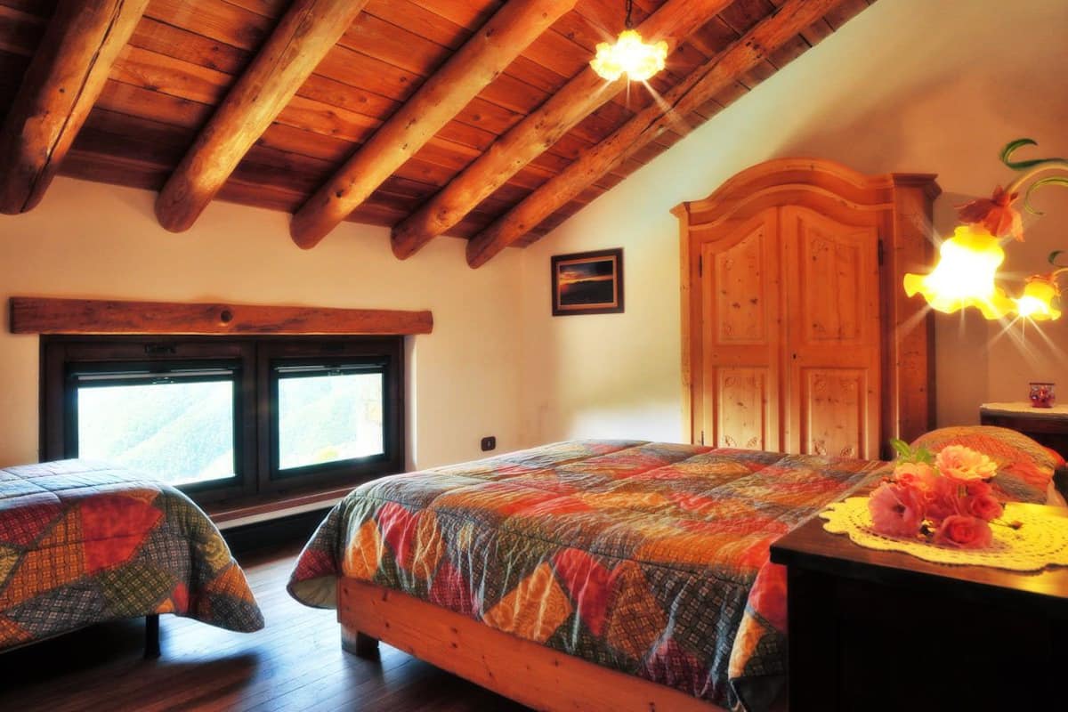 Un dormitorio con dos camas, vigas de madera, un armario grande y una ventana con vistas.
