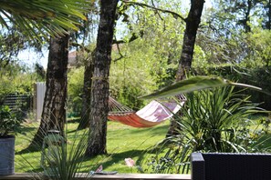 A hammock tied between two trees in a garden with potted plants and a wooden bench. - La Folie (Breuil-Barret)