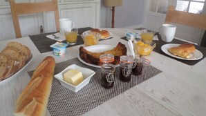 Ein Frühstückstisch mit Brot, Gebäck, Obst und Getränken.