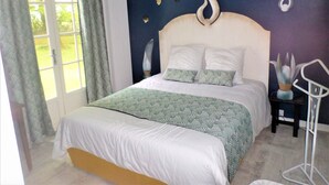 Ein Schlafzimmer mit einem großen Bett, einem Nachttisch, einem Sessel und einem Fenster mit Vorhängen.