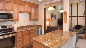 A modern kitchen with granite countertops, stainless steel appliances, and wooden cabinetry. - Vantage Point 210 3 Bedroom Condo by RedAwning (Vail)