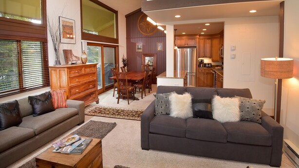 A spacious living room with a sofa, a coffee table, and a dining area with a table and chairs. - Vantage Point 210 3 Bedroom Condo by RedAwning (Vail)