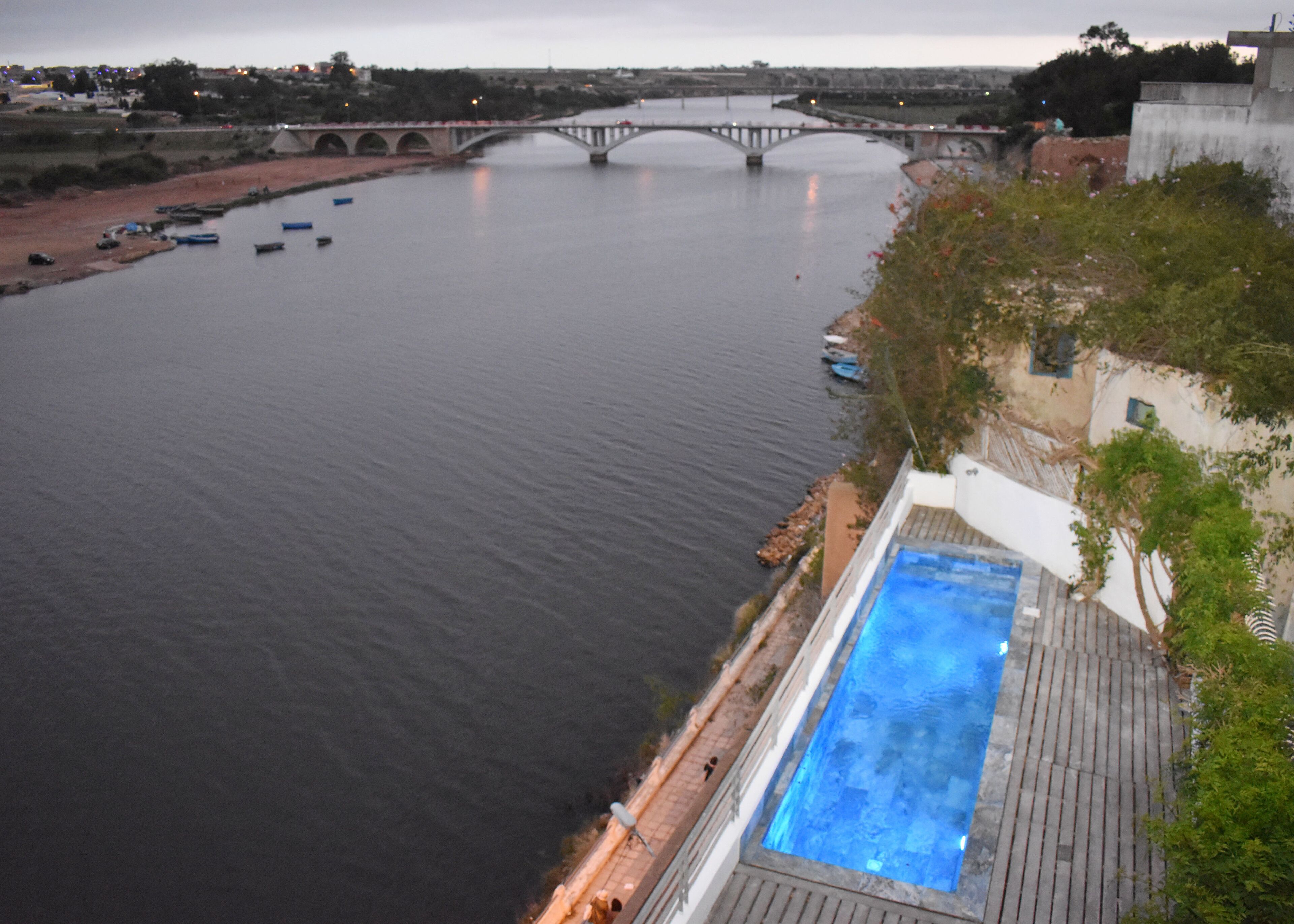 Un río con un puente, barcos y una piscina.