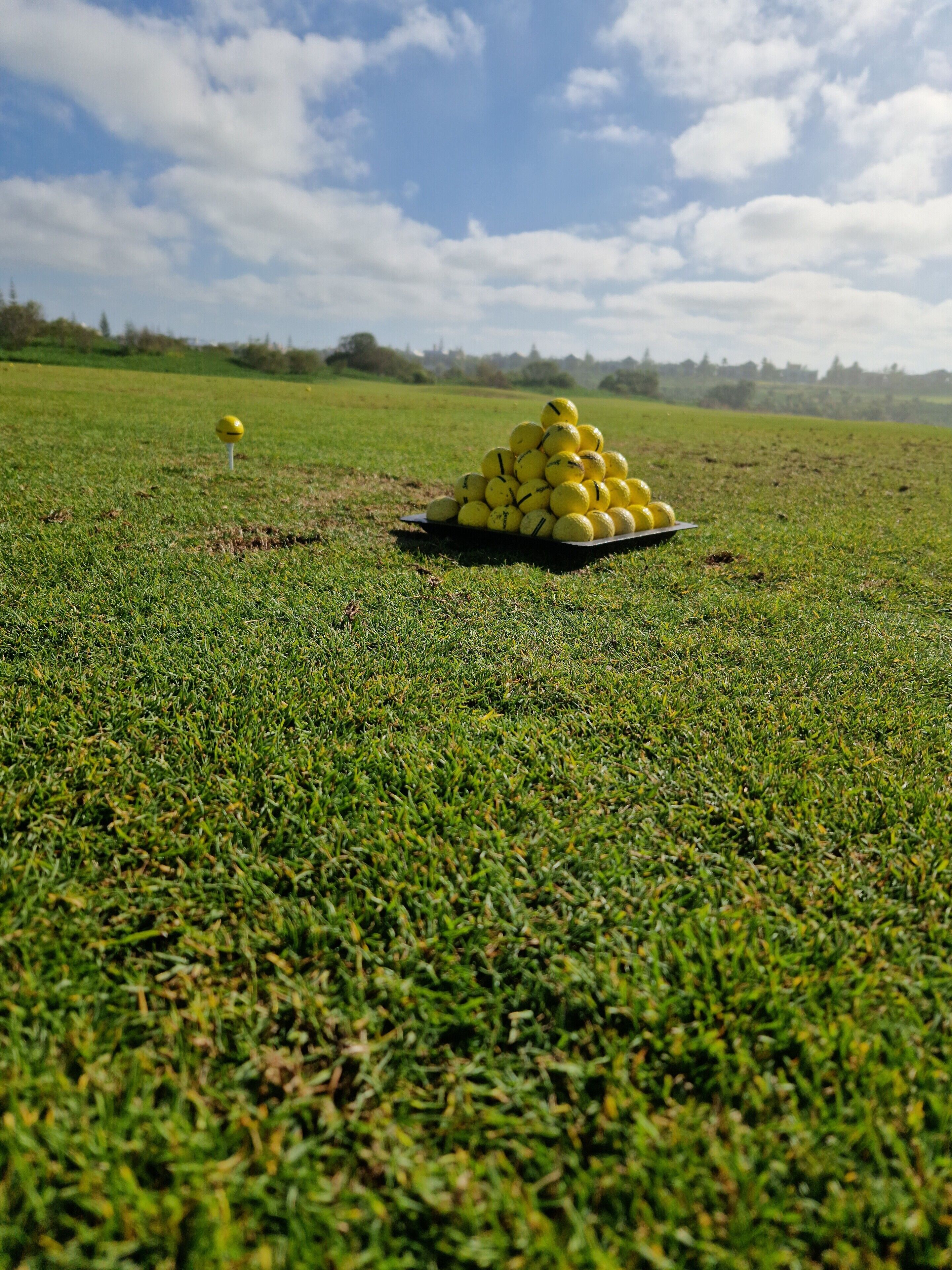A golf course with a pile of golf balls on the grass.