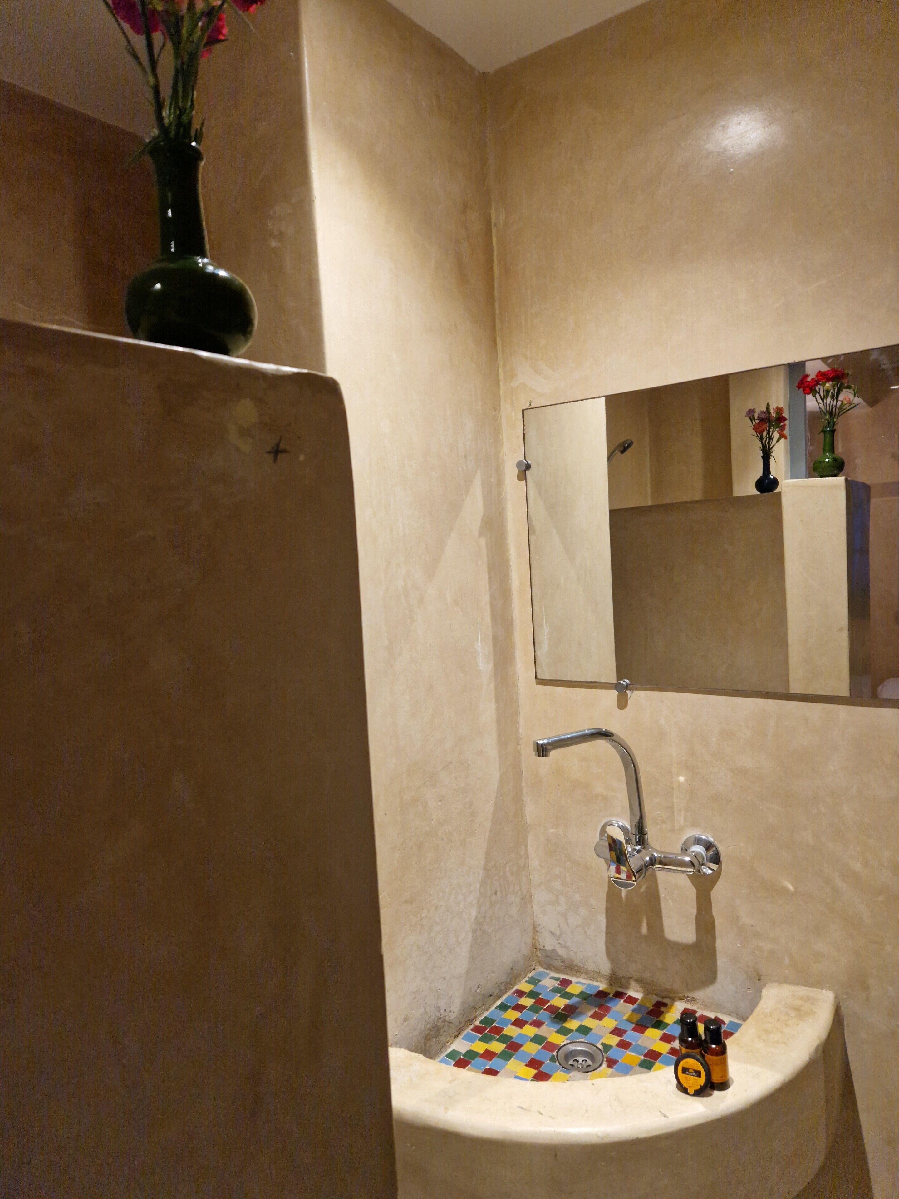 A bathroom with a sink, mirror, and a tiled floor.