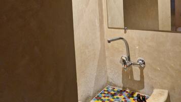 A bathroom with a sink, mirror, and a tiled floor.