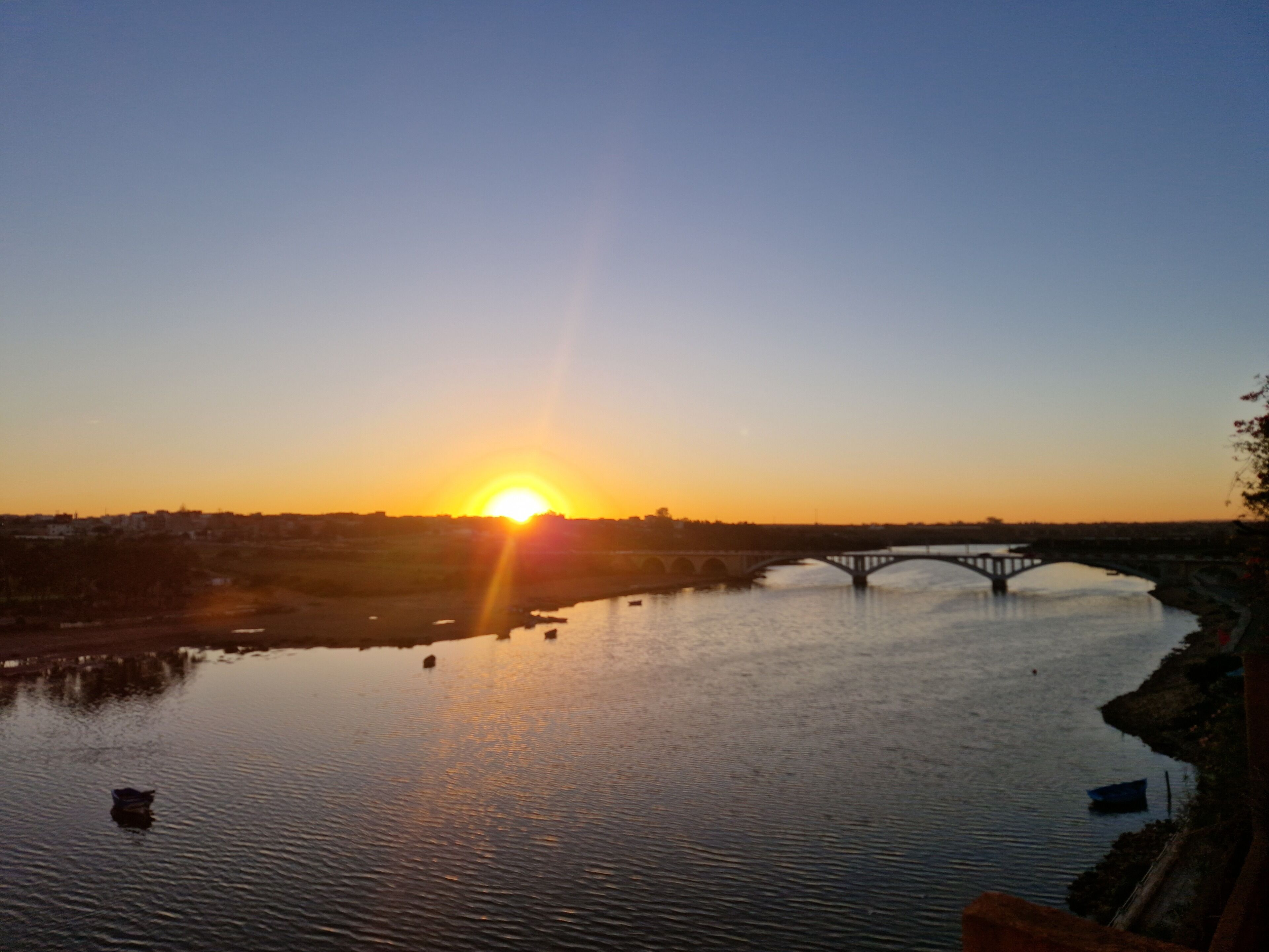 Un atardecer sobre un río con un puente.