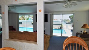 A room with a view of a pool, a ceiling fan, and a sofa. - 108 W. Morningside 2 Bedroom Condo by RedAwning (South Padre Island)