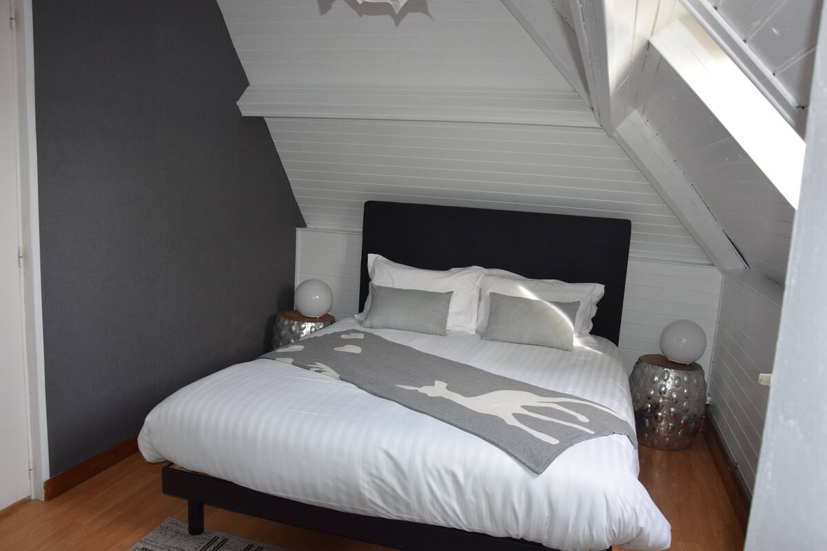 A bedroom with a bed, two bedside tables, a nightstand, and a window.