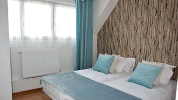 Una camera da letto con un letto, una finestra con tende, un termosifone e un muro in legno.