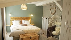 Une chambre à coucher avec une tête de lit en bois, un grand lit avec une literie blanche, une commode en bois et un fauteuil décoratif.