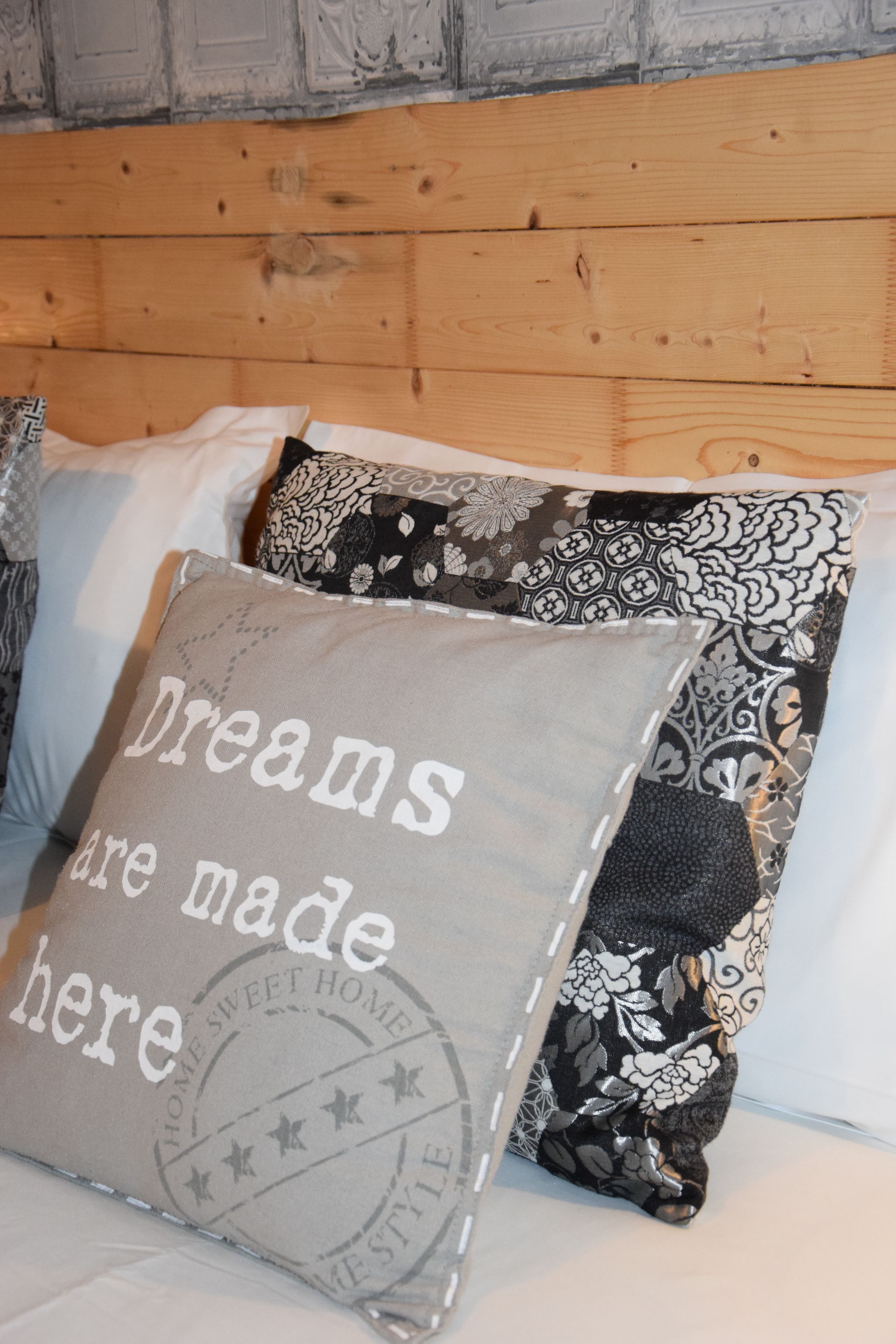 Ein Bett mit Kissen, eines mit Aufdruck und eines mit Blumenmuster.
