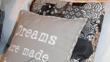 A bed with pillows, one with a printed message and another with a floral pattern.