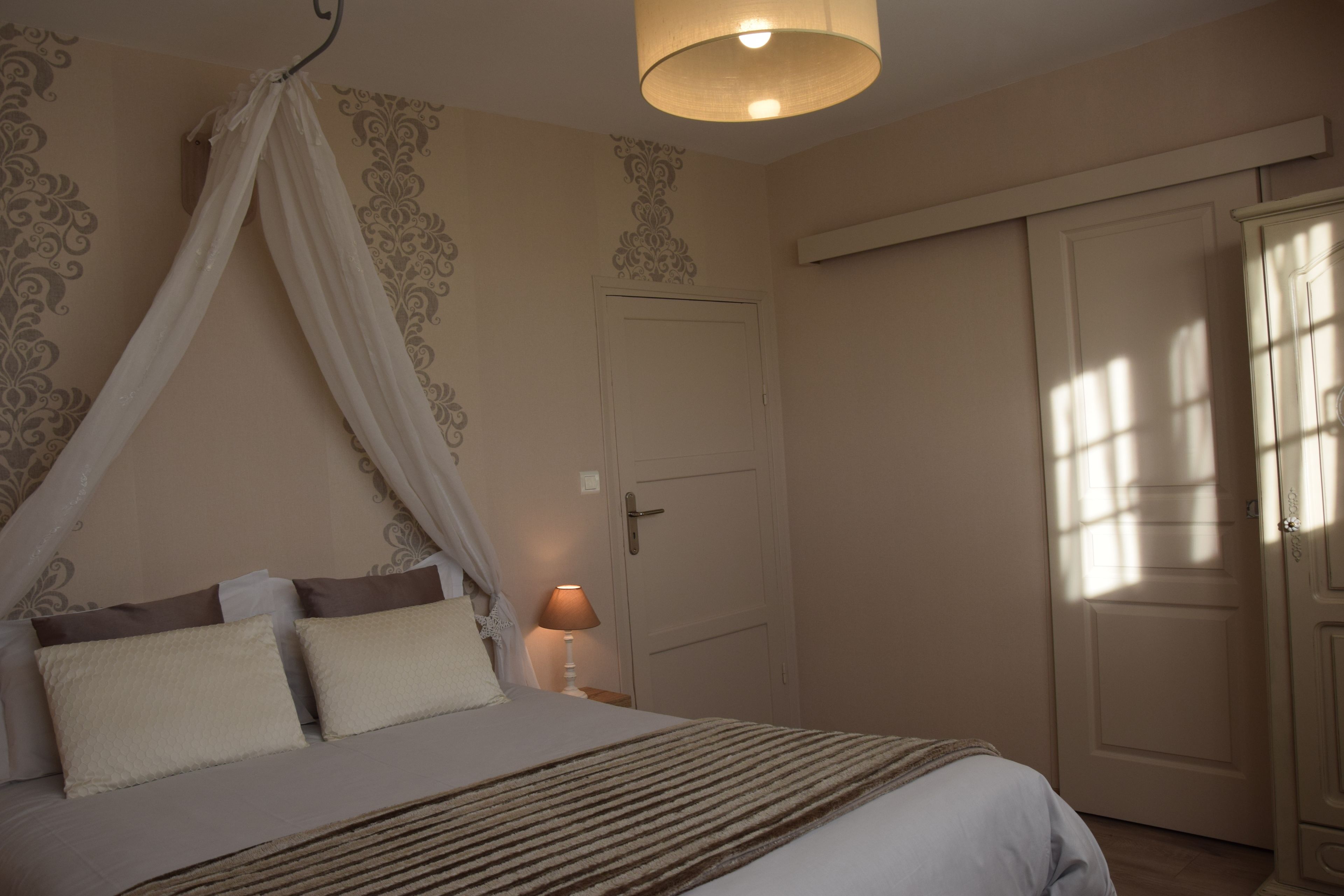 Una camera da letto con un letto a baldacchino, una lampada da comodino e un armadio.