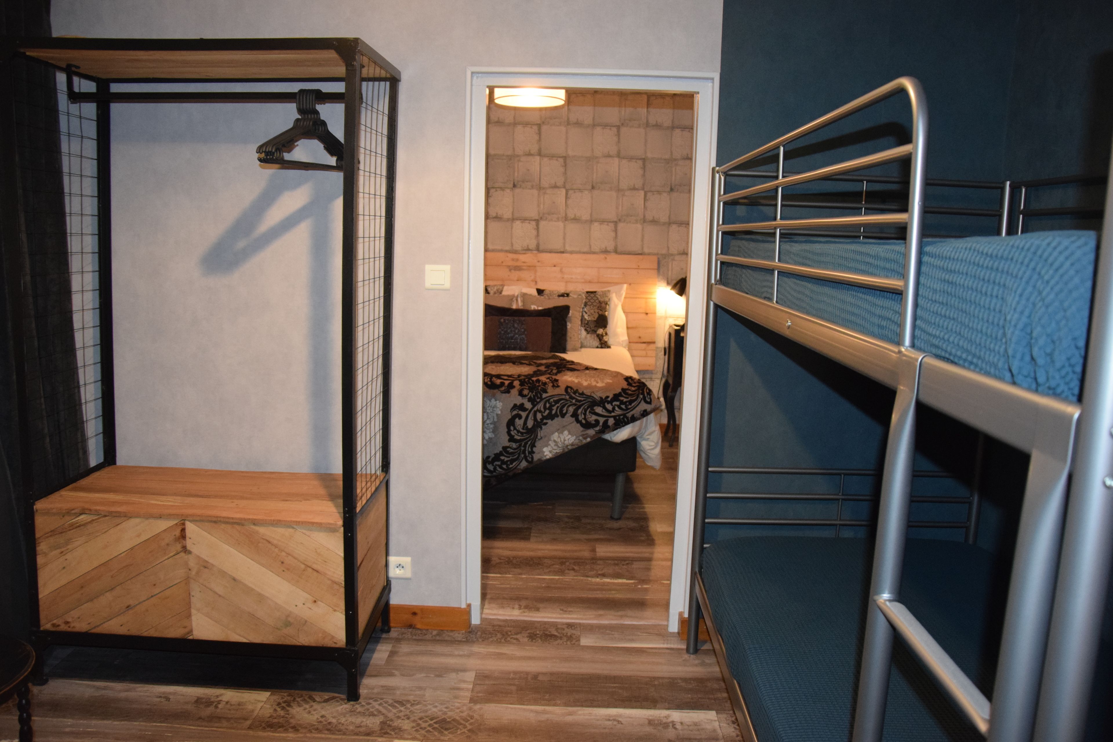 Habitación pequeña con literas, un banco de madera y una lámpara colgante.