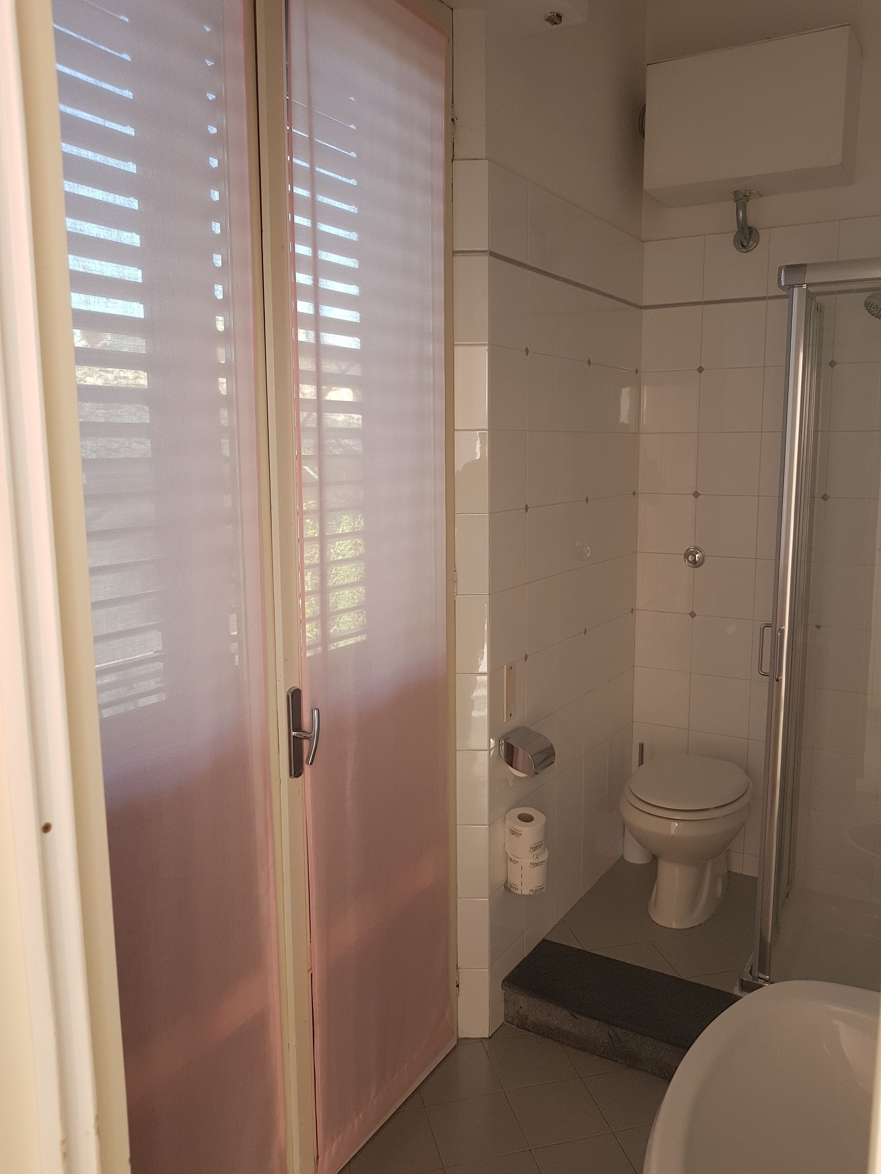 Un bagno con il water, una doccia e un dispenser di carta igienica.