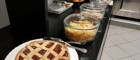 A buffet table with a pie, cereal, and fruits.