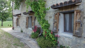 A stone building with wooden shutters, a vine-covered wall, and a stone pathway leading to the entrance. - Bed and breakfast Monte Bibele (Monterenzio)