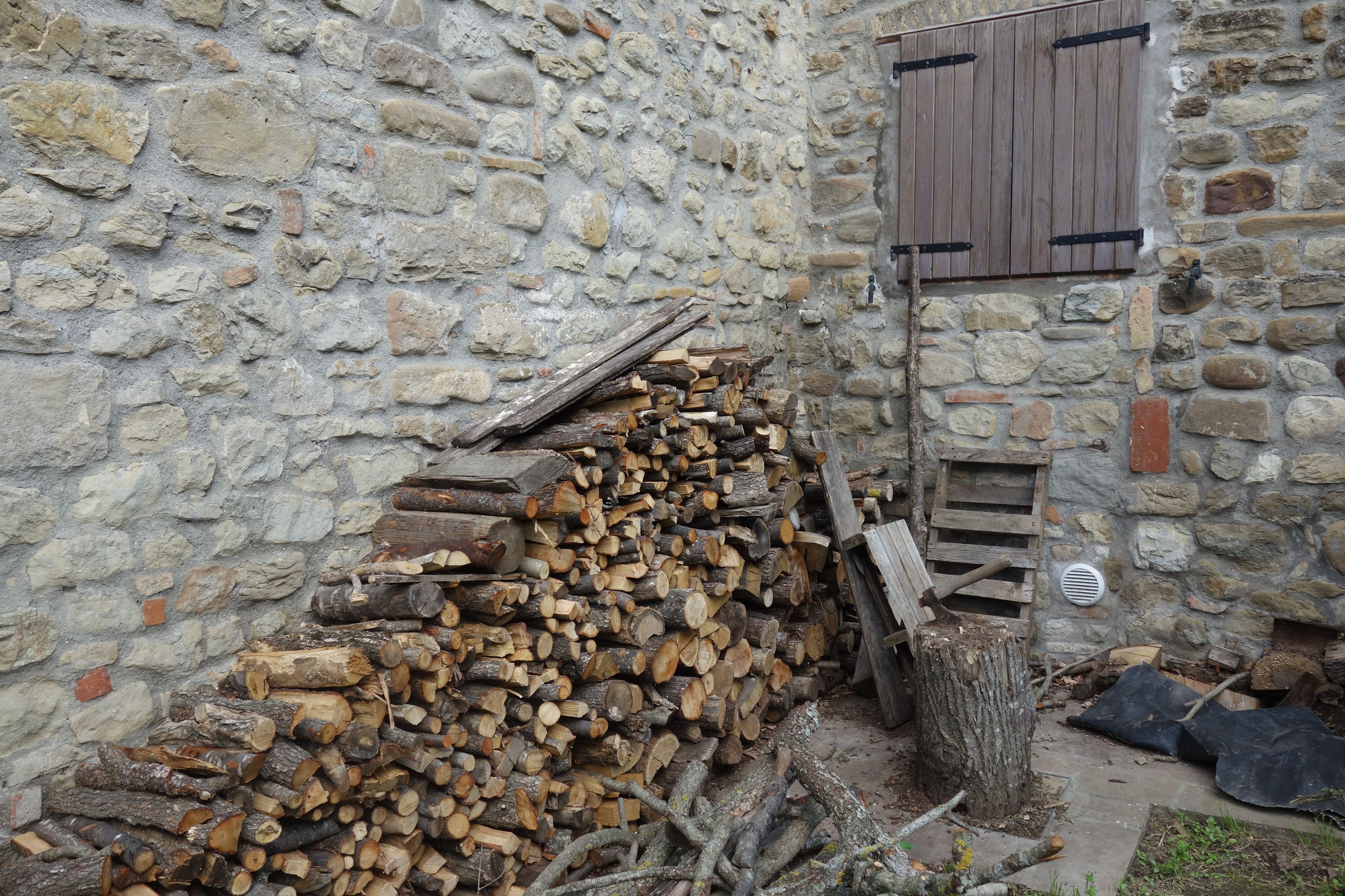 A stone wall with a wooden door and a pile of firewood against it.