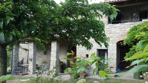 A stone building with a courtyard, outdoor seating, and greenery. - Bed and breakfast Monte Bibele (Monterenzio)