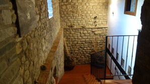 A stone-walled corridor with a tiled floor, a small staircase with a metal railing, and a window with a view of the sky. - Bed and breakfast Monte Bibele (Monterenzio)