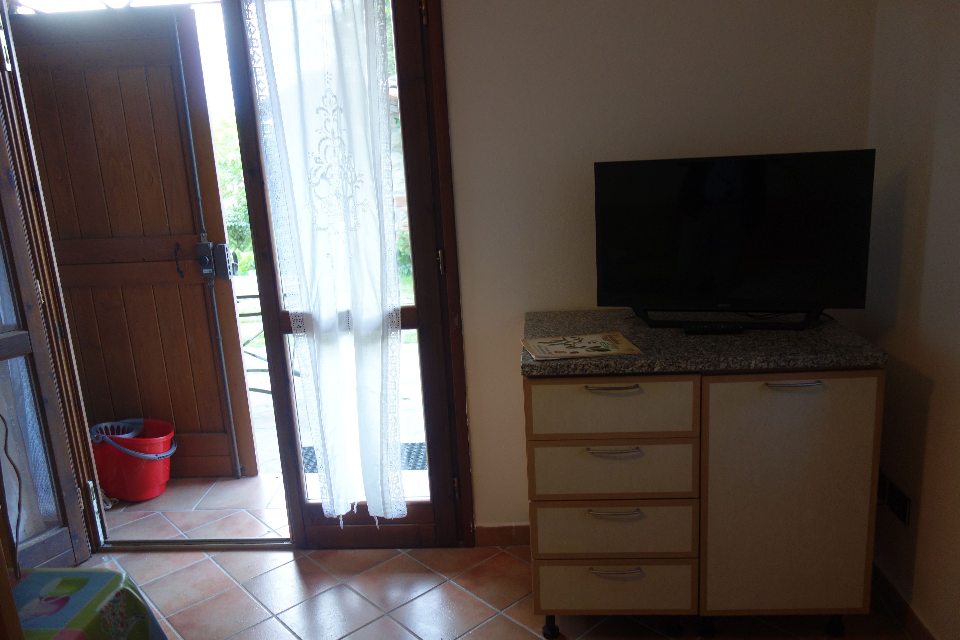 Ein Zimmer mit Holztür, einem Fernseher auf einer Granit-Arbeitsplatte und einem roten Eimer in der Nähe der Tür.