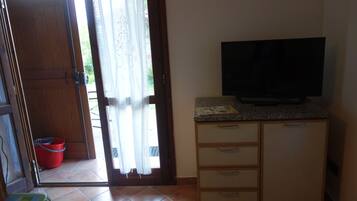Ein Zimmer mit Holztür, einem Fernseher auf einer Granit-Arbeitsplatte und einem roten Eimer in der Nähe der Tür.