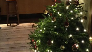 A kitchen with a wooden bar counter, a stool, and a Christmas tree with lights and ornaments. - Haus Alpenrose (Waidring)